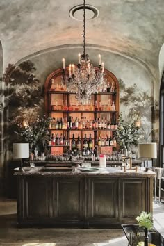 an elegant bar with chandelier and wine bottles