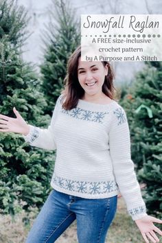 a woman standing in front of christmas trees wearing a snowflake raglan sweater