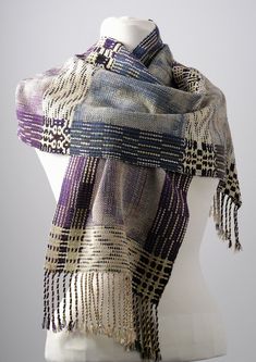 a white mannequin head wearing a purple and black scarf with tassels