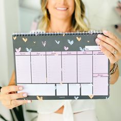 a woman holding up a planner with hearts on it