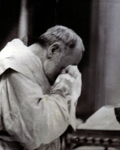 an old black and white photo of a man sitting at a table with his hands to his face