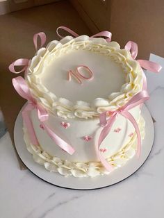 a white cake with pink bows and the number ten on it's top is sitting on a table