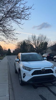 a white toyota rav parked on the side of a road next to a tree