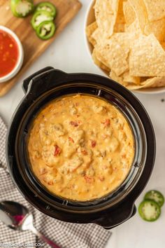 a crock pot filled with salsa and tortilla chips next to some dipping sauce