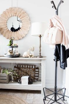 a white table with a mirror and coat rack on top of it next to a lamp