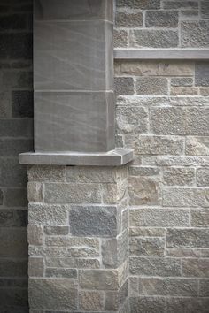 an orange cat sitting on the ledge of a stone building next to a fire hydrant