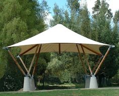 a large white tent sitting on top of a lush green park covered in trees and grass