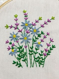 a close up of a embroidery on a piece of cloth with flowers in the middle