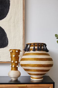 two vases sitting on top of a dresser next to a painting