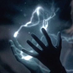 a person's hand reaching up to the lightening behind them