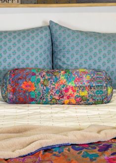 a colorful bag sitting on top of a bed next to two pillows and a blanket