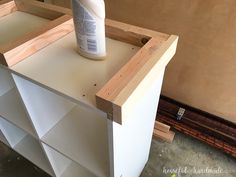 a bottle of glue sitting on top of a white cabinet next to some wood planks