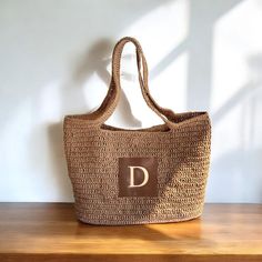 a brown bag sitting on top of a wooden table next to a white wall with the letter d