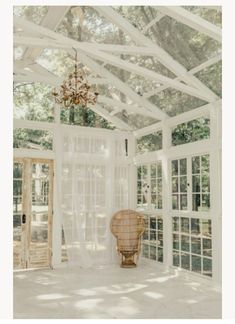 the inside of a house with white walls and windows, chandelier hanging from the ceiling