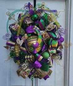 a wreath with mardi gras decorations hanging on the front door