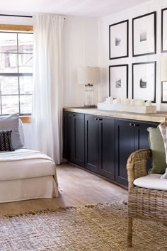 a living room filled with furniture and framed pictures on the wall above a bed in front of a window