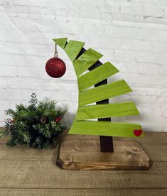 Bring a touch of the grinch to your holiday decor with this charming wooden Christmas tree, featuring a delightful bent design that adds character and uniqueness. Topped with a vibrant shatterproof red ornament, this Grinch-inspired piece captures the playful spirit of the season, making it a perfect addition to your festive celebrations. Ideal for any space, it combines rustic charm with a fun twist, ensuring your home is filled with holiday cheer.  Suitable for indoor or outdoor decor.  *Ornam Wooden Grinch Tree Diy, Grinch Christmas Tree Diy Wood, Grinch Pallet Tree, Wood Tree Decorations, Wooden Grinch Tree, Wood Grinch Tree, Wooden Grinch, The Grinch Christmas Tree