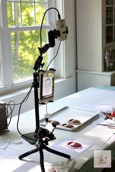 a tripod sitting on top of a table next to an open window with food in front of it