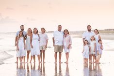 a family standing on the beach in front of the ocean at sunset with their arms around each other