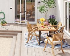 an outdoor dining table and chairs on a deck with potted plants in the background