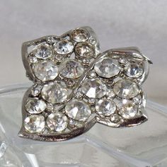 This  vintage silver rhinestone leaf brooch is just beautiful!!  It features a rhodium plated silver leaf with an open design filled with clear round rhinestones in different sizes.   Rolling C-clasp closure.    A perfect addition to your vintage jewelry collection!Size:  2-1/4" x 2"Approximate Date:   1950s Hallmarks/signature:  NoneCondition:  ExcellentColors:  Silver, ClearStyle:  Figural, 1950s Jewelry, Leaf, Nature, Leaf JewelryFor more vintage treasures, please visit my shop at waalaa.etsy Silver Rhinestone Brooches For Anniversary, Silver Crystal Brooch For Anniversary, Silver Crystal Brooches For Anniversary, Silver Crystal Anniversary Brooches, Silver Crystal Brooch With Sparkling Stones, Silver Crystal Brooches With Sparkling Stones, Silver Brooches With Sparkling Stones For Gifts, Sparkling Silver Brooch For Anniversary, Silver Sparkling Brooches For Anniversary