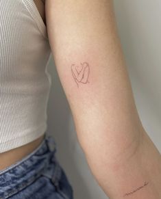 a woman's arm with a small heart tattoo on the left side of her arm