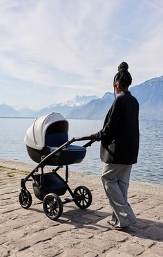 a woman pushing a stroller by the water