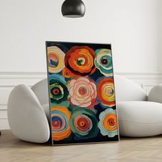 an abstract painting is displayed on the floor in front of white chairs and a black lamp