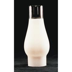 a white vase sitting on top of a wooden table next to a black wall and floor