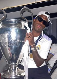 a man sitting in the back of a car holding up a silver trophy with both hands