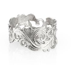 an ornate silver ring on a white background