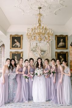 a group of women standing next to each other in front of a chandelier