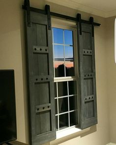 an open window with shutters in front of a flat screen tv mounted on a wall