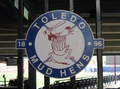 a blue and white sign that says toledo mud hews in front of a baseball field