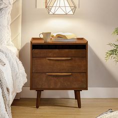 a bedside table with a book and cup on it