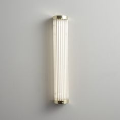 a wall mounted light on the side of a white wall with gold trimmings