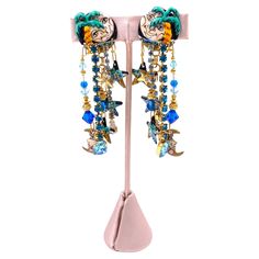 Add a touch of whimsy to your outfit with our Lunch at the Ritz Earrings, Moon Over Miami. Featuring a painted moon and stars detail with blue and gold beading, these dangle earrings are adorned with large rhinestones for an eye-catching look. Perfect for any occasion! Length: 3.5" Width: 1" Painted Moon, Feather Heels, Earrings Moon, Wedding Guest Shoes, The Ritz, Summer Special, Belt Purse, Bridal Salon, Moon And Stars