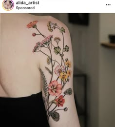 a woman's shoulder with flowers and leaves painted on the back of her arm