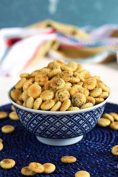 a bowl filled with crackers sitting on top of a blue place mat next to a plate