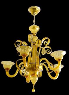 a yellow chandelier with five lights hanging from it's sides and an intricate design on the bottom