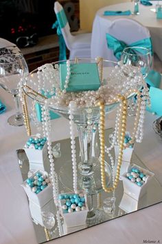 a table topped with a glass vase filled with pearls and other items on top of it