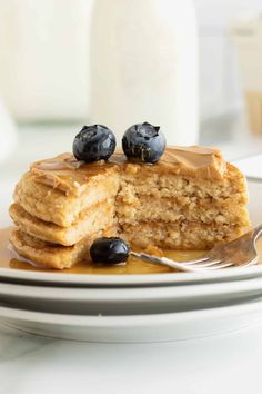 a stack of pancakes with syrup and blueberries