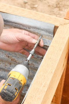 a man using a drill to attach the side of a piece of wood with a screwdriver