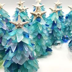 some blue and green glass trees with starfish decorations on them, sitting next to each other