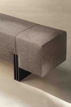 an upholstered bench with black legs and a checkered pattern on the back