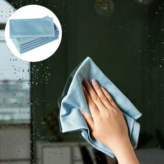 a hand holding a cloth on top of a window sill with water droplets all over it