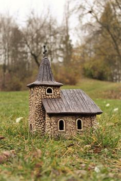 a small house made out of rocks in the grass