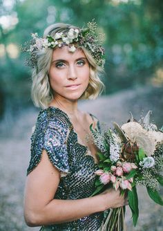 a woman holding a bouquet of flowers in her hand and wearing a dress with sequins on it