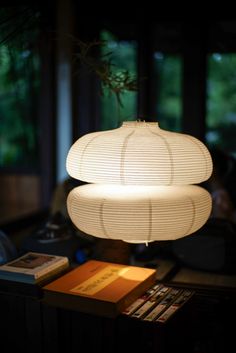 a white lamp sitting on top of a table next to a book and some books