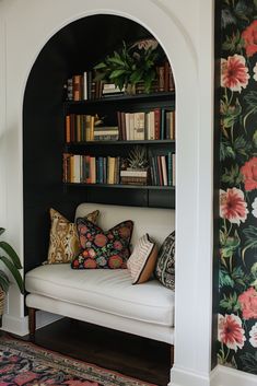 a white couch sitting in front of a book shelf filled with books